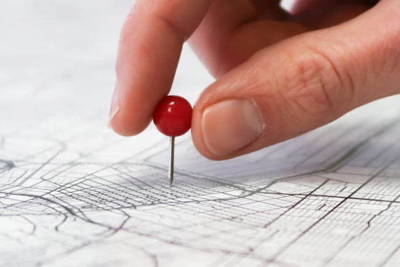 Close-up of a hand placing a pushpin into a detailed map