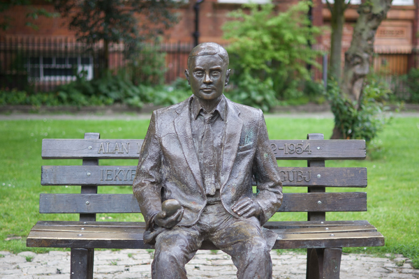 Alan Turing sitting on a bench